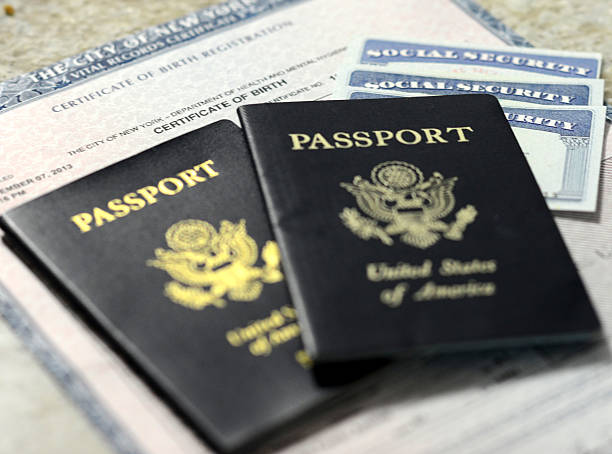 Diffterent forms of identification. pictured are three social security cards on  top of a birth certificate covered by two american passports.