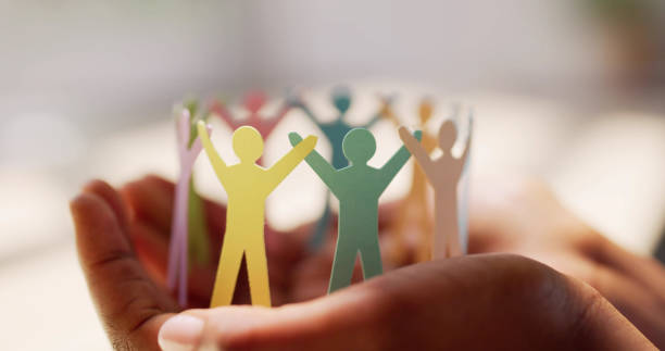 paper humans in different colors of the rainbow holding hands, held by a pair of hands. How to Update Your Passport Gender Marker After the New Court Ruling